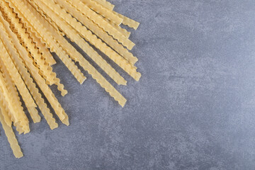 Bunch of various-shaped dry pasta on stone background