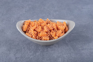 Raw heart-shaped pasta in ceramic bowl
