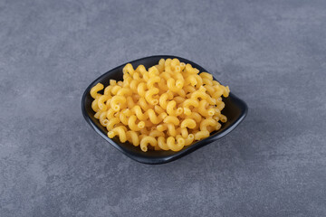 Raw dry macaroni in black bowl