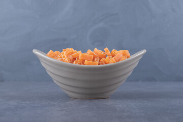 Raw heart-shaped pasta in ceramic bowl