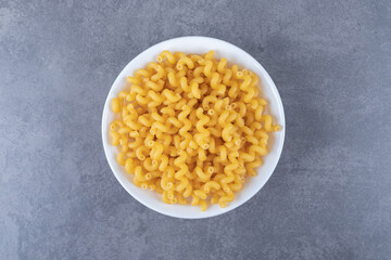 Raw elbow macaroni on white plate