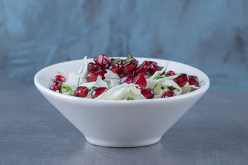 Pomegranate arils and grated vegetable, on the marble background