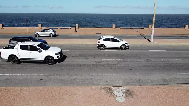 Street aerial side view with cars and people passing in rambla promenade of Montevideo, Uruguay