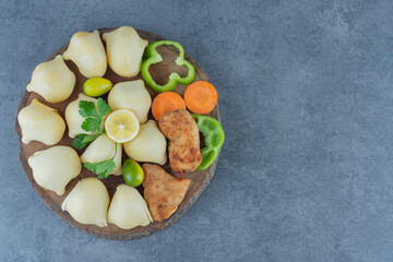 Boiled pasta and chicken wings on wood piece
