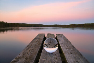 Glass ball on a wooden pier at a Swedish lake at evening hour. Nature Scandinavia