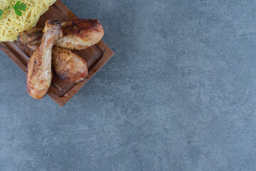 Grilled chicken legs and spaghetti on wooden board