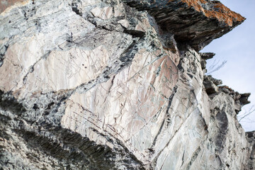 Old rock carvings of an ancient man on rocks in Siberia. The drawings depict animals and people