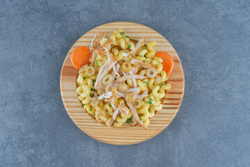 Delicious pasta with chopped chicken on wooden plate