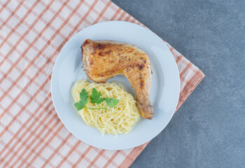 Chicken leg and spaghetti on white plate