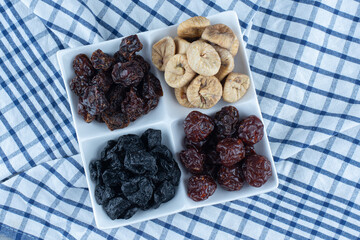 Different dried fruits in bowl, on the tea towel, on the marble background