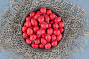 Red candies in the cup on the trivet, on the marble background