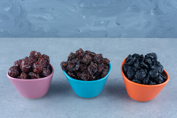 Three bowls of dried fruit , on the marble background