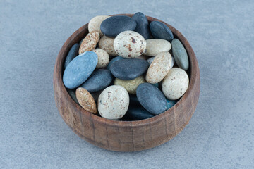 Pebble stone candies in a bowl, on the marble background