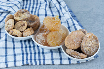 Various dried fruits in the bowl, on the tea towel, on the marble background