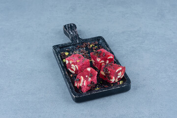 Turkish delights and raisins on the cutting board , on marble background
