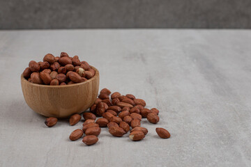 Unpeeled organic peanuts in wooden bowl