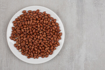 Pile of fresh peanuts on white plate