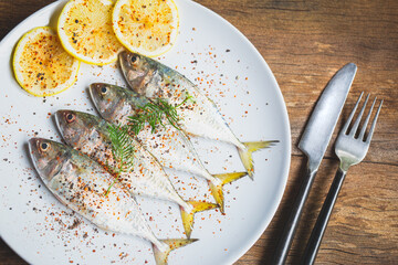 Fresh fish mackerel and ingredients for cooking. Spices with black pepper, cayenne pepper, salt, lemon on white dish.