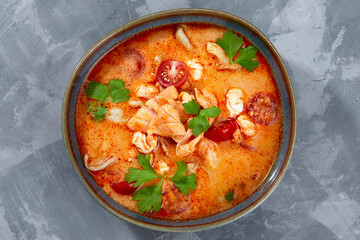 Traditional Thai food cuisine. Tom Yum spicy soup in black bowl on grey background. Thai food concept. Top view