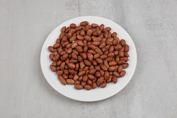 Pile of fresh peanuts on white plate