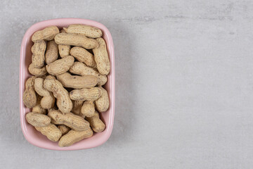Tasty raw peanuts in pink bowl
