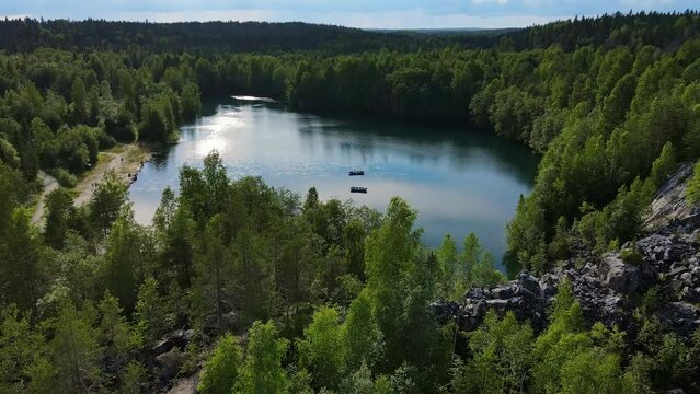 Boats float on the lake, the shores of which are covered with coniferous forest