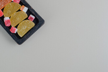 A dark wooden board full of colorful sugary marmalades