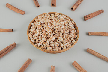 A wooden bowl full of healthy cereals with cinnamon sticks