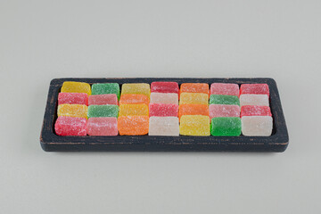 A dark wooden board full of colorful sugary marmalades