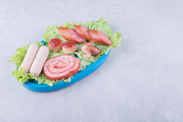 Assortment of tasty sausages on blue plate