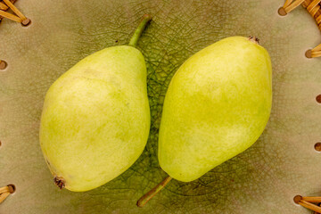 Fototapeta na wymiar Two sweet pears on a ceramic dish, macro, top view.