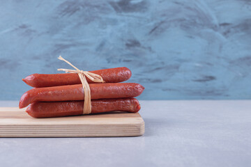 Smoked sausages tied with rope on wooden board
