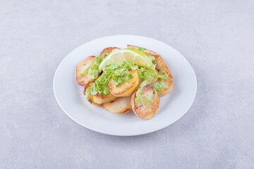 Fried potatoes garnished with lemon on white plate