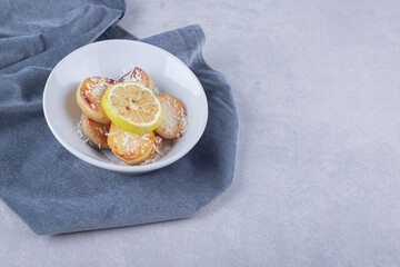 Fried potatoes garnished with grated cheese and lemon on white plate