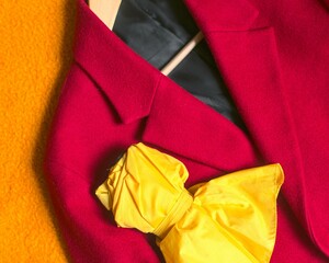 Manteau rouge et parapluie jaune replié sur fond orange mode