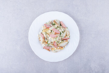 Plate of salad with sausages on stone background