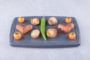 Fried sausages and potatoes on dark board