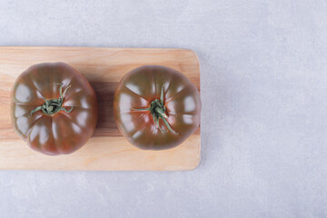 Two ripe tomatoes on wooden board