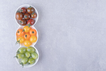 Colorful cherry tomatoes in white bowls