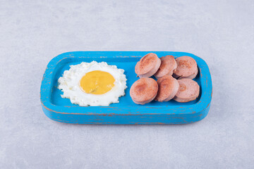 Sliced fried sausages and egg on blue plate