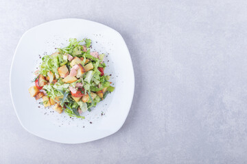 Plate of fresh salad with sausages on stone background