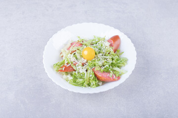 Sliced smoked sausages, lettuce and egg yolk in white bowl