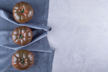 Three ripe tomatoes on blue cloth