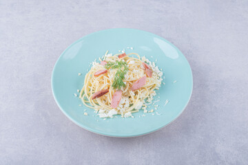 Boiled spaghetti with sliced sausages on blue plate