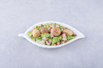 Sliced fried sausages and lettuce in white bowl