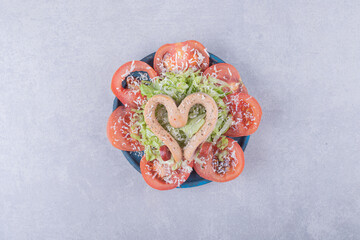 Boiled sausages shaped like heart and tomato slices