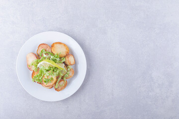 Fried potatoes decorated with lemon and lettuce on white plate