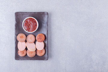 Sliced sausages with ketchup on dark plate