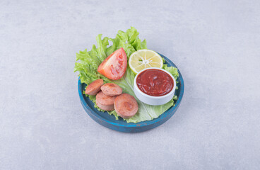 Tasty grilled sausages and ketchup on blue plate