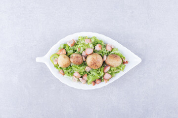 Sliced fried sausages and lettuce in white bowl